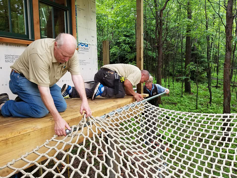 Attaching a climbing net deck to the tree house.