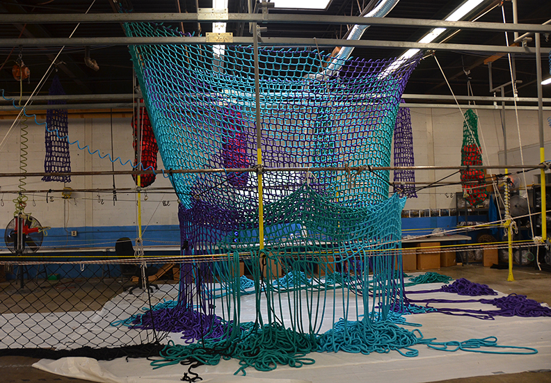 A Colorful climbing net being manufactured by hand.