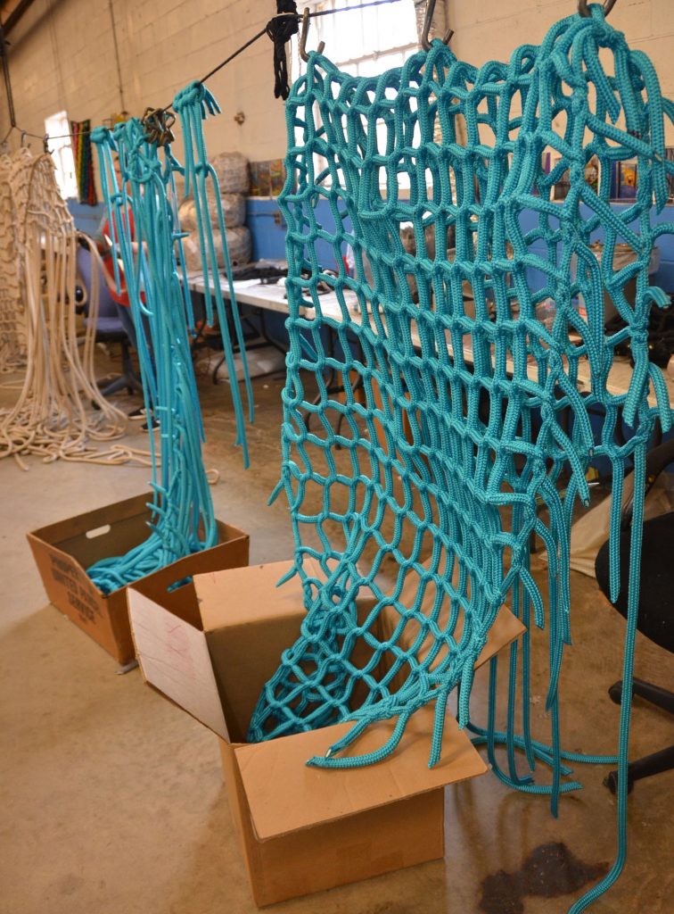 A teal climbing net is made by hand.