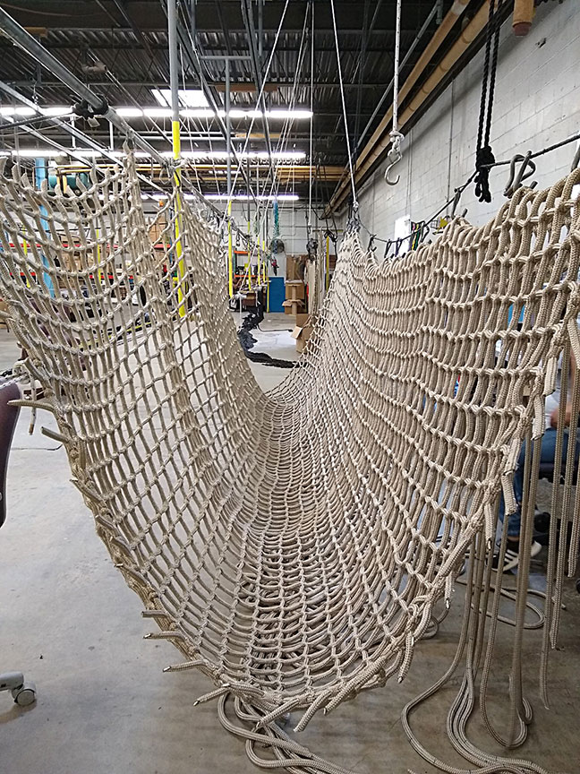 A rope net bridge being manufactured.