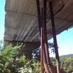 Netting supports a layer of tarps suspended under a bridge undergoing restoration.