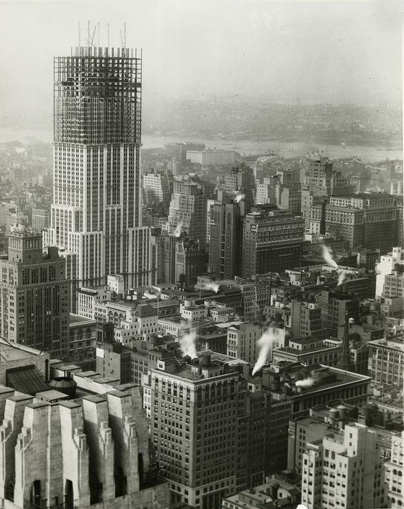 The Empire State Building during construction, raises far above the rest of the neighborhood.