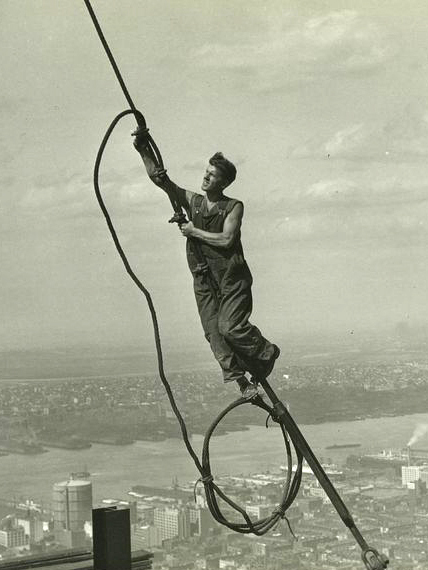 A steel worker climbs a cable.