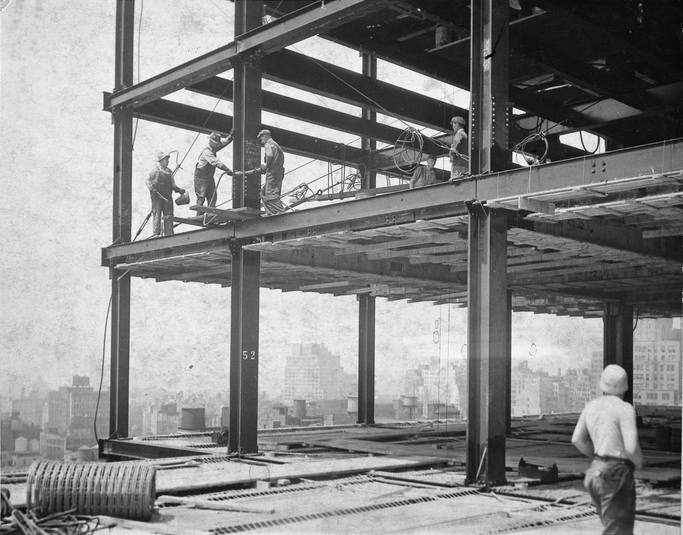 Steel workers walk the beams of the Empire State Building during its construction.