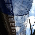 A suspended safety net attached to a bridge by cables protects pedestrians and traffic from falling debris.