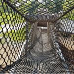 A netted tunnel bridge in a playground.