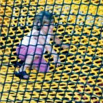 A Little girl sitting on a yellow climbing net.