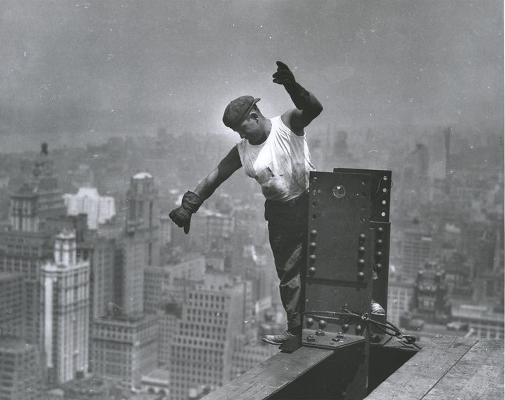 A steel worker balances on a beam.