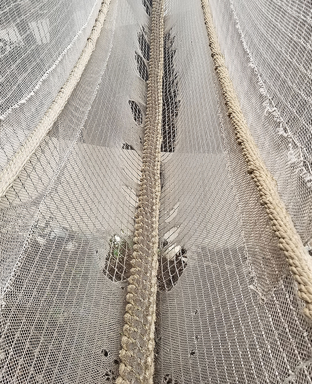 A climbing net showing extreme wear and damage.