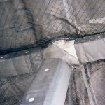 Debris netting containing spalling concrete in a garage.